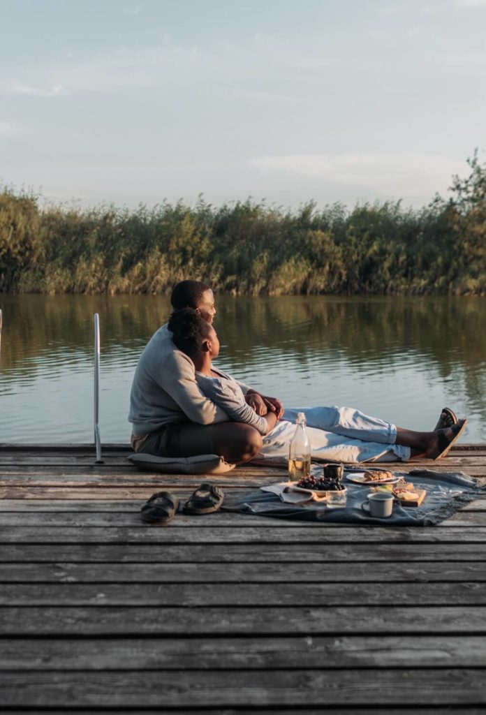 couple having picnic on dock by lake