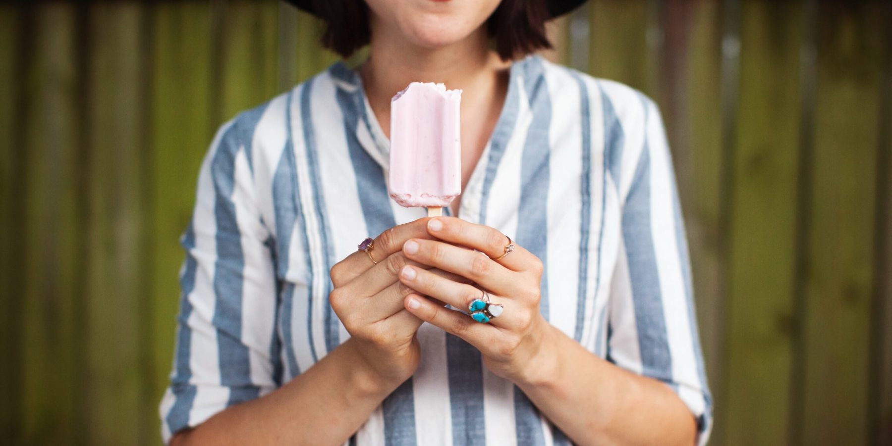 woman holding pink popsicle