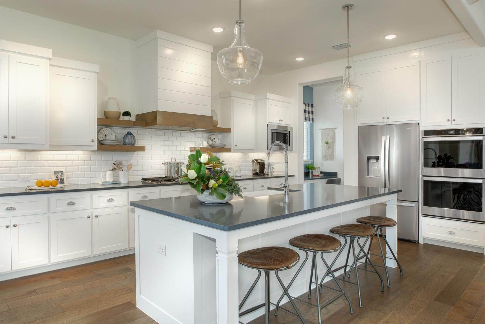 A white kitchen with a center island and stools, perfect for new homes seeking the tranquility of nature and nearby trails.