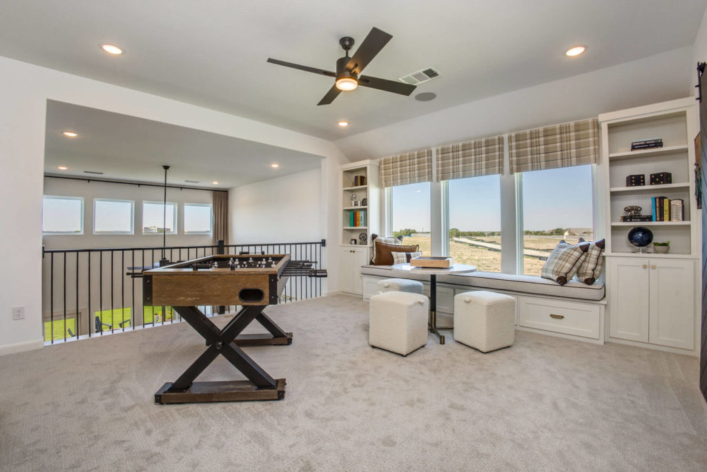 A living room with a foosball table and a ceiling fan in a new home.