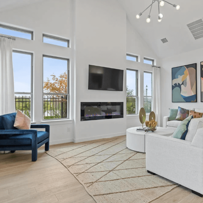 A living room with large windows overlooking a serene lake and featuring a cozy fireplace.