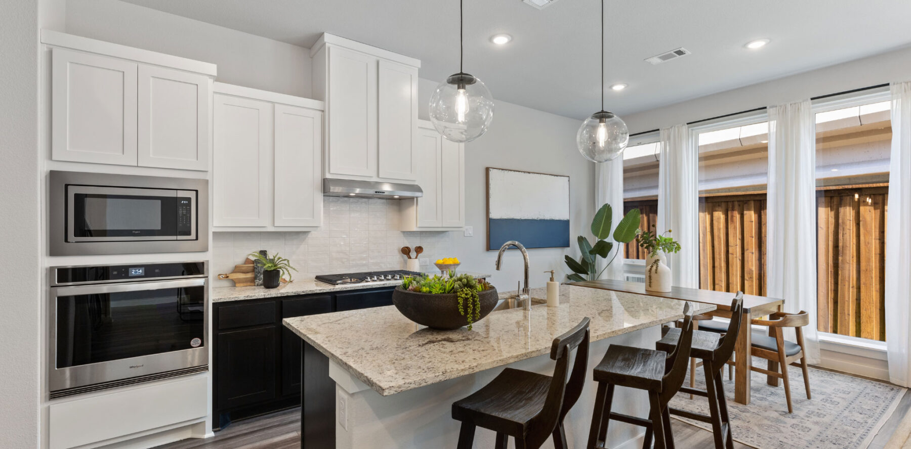 A kitchen in a new home with white cabinets and stainless steel appliances.