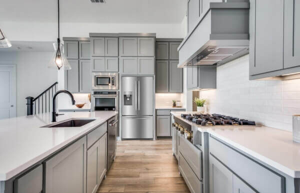 A new kitchen with gray cabinets and stainless steel appliances in a Texas lake home.