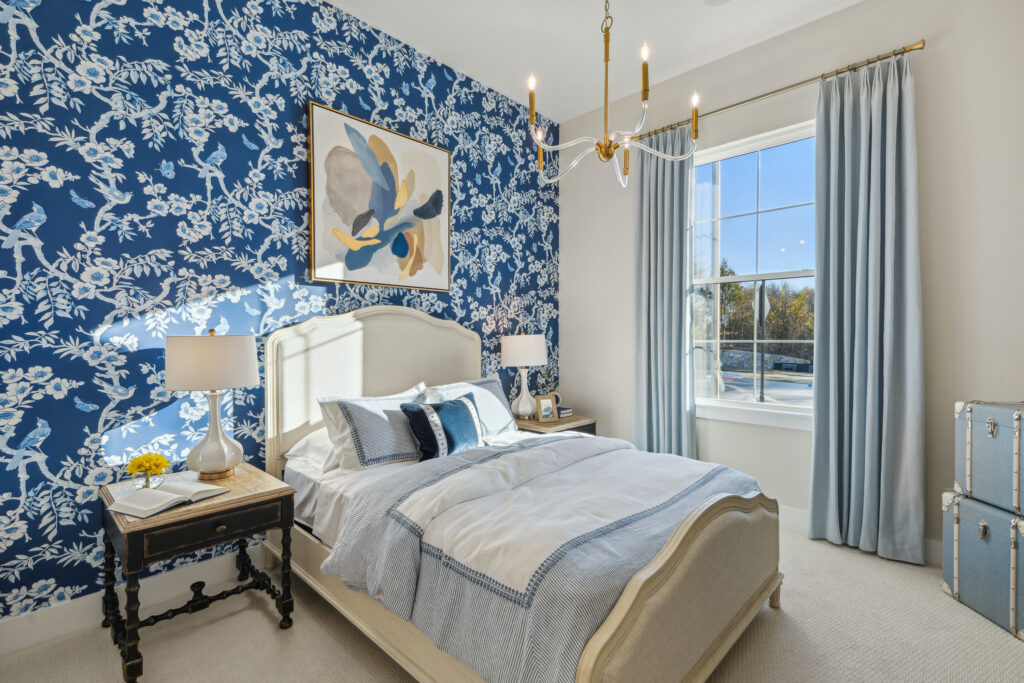 A bedroom with blue and white floral wallpaper.