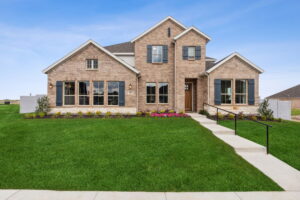 Two-story brick house in McKinney, TX with a neatly manicured lawn and a concrete walkway leading to the front door under a clear blue sky.