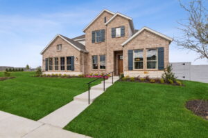 A modern two-story brick house in McKinney, TX, with a lush green lawn and landscaped garden under a clear blue sky.