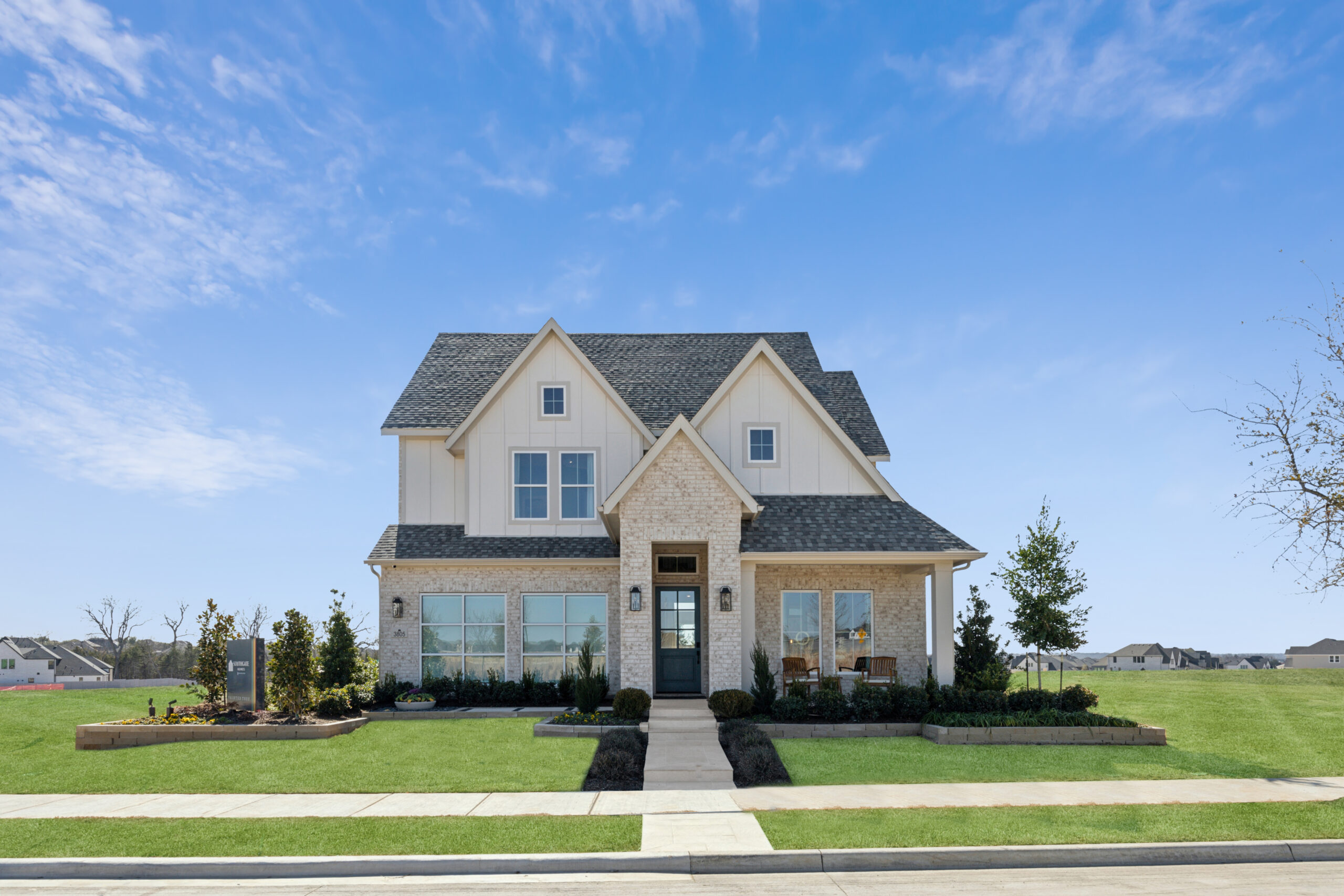 Nestled in McKinney, TX, this two-story house boasts a grey roof and light exterior. Large windows invite natural light, while a well-kept lawn and shrubs enhance the charm of this new home on a clear day.