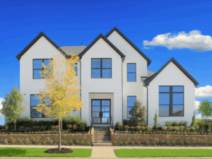 A modern two-story white house with large windows, a central walkway, landscaped shrubs, and a small tree in the front yard under a blue sky—crafted by Drees Custom Homes in the Painted Tree community of TX.