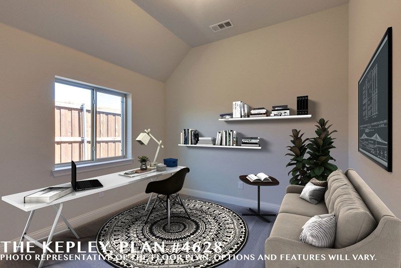 A modern home office with a desk, laptop, chair, sofa, plant, wall shelves with books, and a large round rug showcases neutral colors and natural light—a perfect space found in many Painted Tree homes for sale in McKinney, Texas.