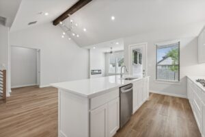 Modern kitchen with white cabinets, a large island, stainless steel appliances, and wood flooring in an open layout—perfect for entertaining. Enjoy bright living areas and spacious design in homes for sale in McKinney Texas.
