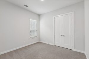 Bright and inviting, this empty room in Painted Tree TX features light gray carpet, white walls, a window with blinds, and double doors—an ideal canvas for your new beginning. Explore more Painted Tree homes for sale today!.