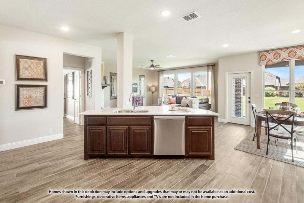 Open-concept kitchen with a central island, dark wood cabinets, and stainless steel appliances in Painted Tree McKinney. Adjacent dining and living areas feature large windows overlooking the backyard—perfect for homes for sale in McKinney, Texas.