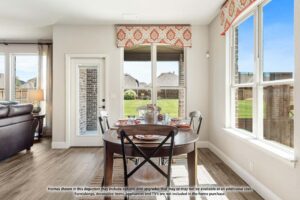 Bright dining area with a round table set for four, large windows, and a door leading to the backyard; living area visible to the left in one of the inviting homes for sale in McKinney, Texas.