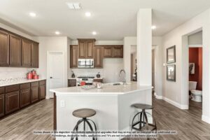 Modern kitchen with dark wood cabinets, stainless steel appliances, a white island with two stools, and tile flooring; a hallway and bathroom are visible in the background—ideal for those seeking Painted Tree homes for sale.