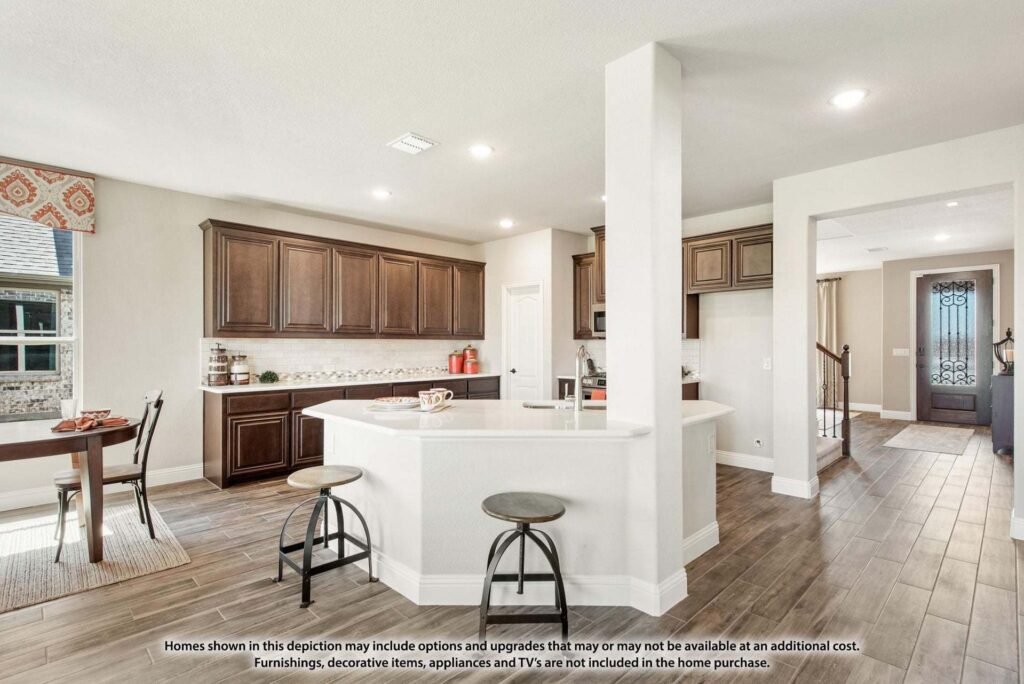 Spacious kitchen with dark wood cabinets, white countertops, a central island with bar stools, and adjacent dining area; enjoy this modern, open layout with wood flooring in sought-after Painted Tree McKinney.