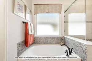 Modern bathroom with a white bathtub, mosaic tile accents, black fixtures, red and white towels, frosted window, and wall art—perfect for relaxing in homes for sale in McKinney Texas.
