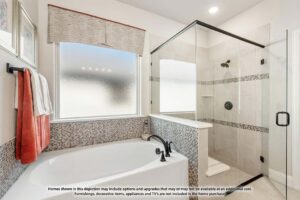 Modern bathroom featuring a large bathtub, glass-enclosed shower, frosted window, and neutral tile accents—perfect for relaxing in homes for sale in McKinney, Texas, including beautiful Painted Tree homes for sale.
