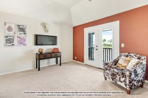 A small room with beige carpet, an accent wall, a mounted TV, a console table, decorative wall art, a patterned armchair, and double glass doors—perfect for those seeking homes for sale in McKinney Texas or the Painted Tree McKinney area.