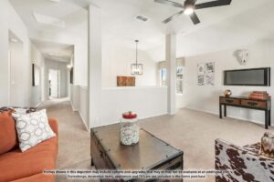 A modern, neutral-toned living area at Painted Tree McKinney features a ceiling fan, wall-mounted TV, desk, and orange couch. A hallway leads to other rooms. Disclaimer text appears at the bottom of the image.