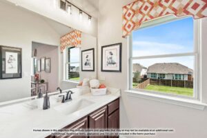 Bathroom with a white countertop, dark wood vanity, and mirror, featuring a window with patterned valance offering a view of the fenced backyard—ideal for those seeking Painted Tree homes for sale in McKinney, Texas.