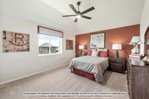 A bedroom with a double bed, two nightstands with lamps, framed wall art, a ceiling fan, a window, and neutral-colored decor—perfect for relaxing after exploring Painted Tree McKinney homes for sale.