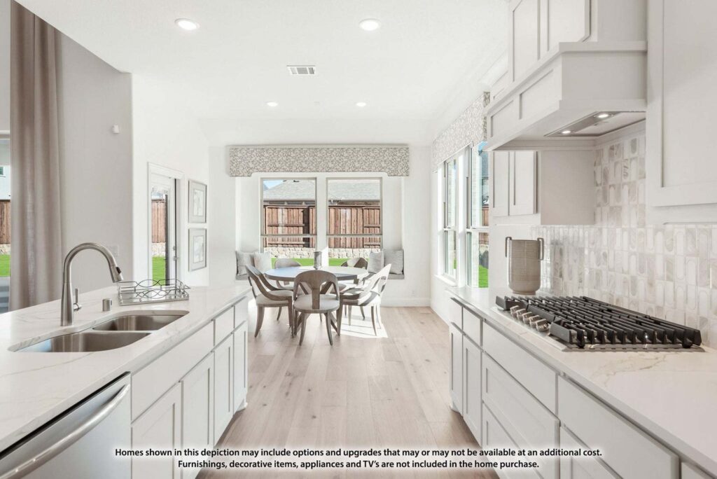 Modern kitchen with white cabinetry, gas stove, and island sink, opening to a dining area with large windows and view of a fenced backyard in desirable Painted Tree McKinney. Explore more stunning homes for sale in McKinney Texas.