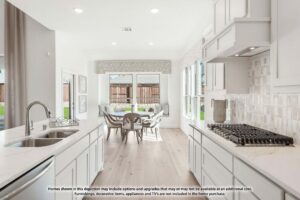 Modern kitchen with white cabinetry, gas stove, and island sink, opening to a dining area with large windows and view of a fenced backyard in desirable Painted Tree McKinney. Explore more stunning homes for sale in McKinney Texas.
