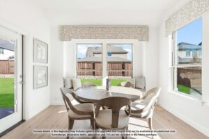 A dining area with a round table and five upholstered chairs, large windows overlooking a fenced backyard, and framed art on a white wall—perfect for enjoying life in Painted Tree TX or browsing homes for sale in McKinney Texas.
