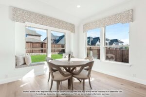 Bright breakfast nook with a round wooden table, four chairs, and large corner windows overlooking fenced backyard—perfect for enjoying mornings in one of the charming painted tree homes for sale in McKinney, Texas.