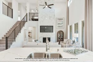 Modern living room with high ceilings, neutral decor, fireplace with TV above, stairway, and large windows—all viewed from a kitchen island with a sink—offers stunning style in sought-after Painted Tree TX homes for sale.