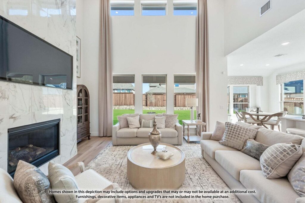 Bright, modern living room with neutral-toned furniture, large windows, marble fireplace, and wall-mounted TV. Sliding doors open to a backyard with a wooden fence—perfect for those seeking homes for sale in McKinney, Texas.