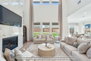Bright, modern living room with neutral-toned furniture, large windows, marble fireplace, and wall-mounted TV. Sliding doors open to a backyard with a wooden fence—perfect for those seeking homes for sale in McKinney, Texas.