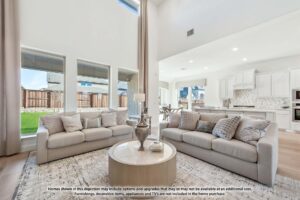 A modern living room with two light-colored sofas, a round coffee table, large windows, and an open kitchen in the background—perfect for those exploring Painted Tree homes for sale in charming McKinney, Texas.