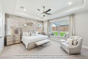 Bright, modern bedroom with a large bed, bench, armchair, dresser, and neutral decor. Large windows offer views of a fenced backyard—perfect for those seeking stylish comfort in homes for sale in McKinney Texas.