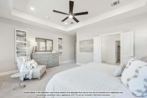 Modern bedroom with a ceiling fan, light gray walls, bed, dresser with mirror, armchair, and abstract artwork; doors lead to adjoining rooms—perfect for those seeking Painted Tree McKinney or Painted Tree homes for sale.