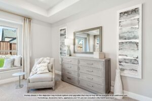 A modern bedroom corner in Painted Tree McKinney features a beige armchair, round side table, large dresser, wall mirror, two abstract paintings, and a window with beige curtains.