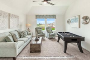 Modern living room with light-colored sofas, wooden coffee table, wall art, and pool table under a ceiling fan. Large window shows a suburban neighborhood view in the heart of Painted Tree McKinney.