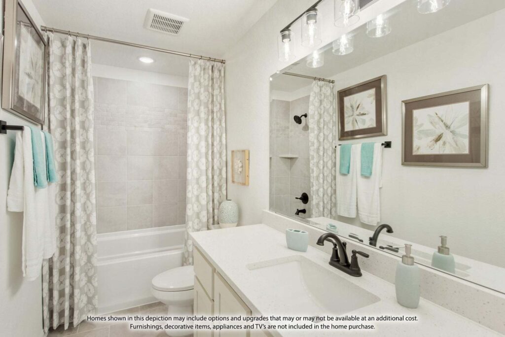 Modern bathroom with a white vanity, black fixtures, and a bathtub with gray tile surround—just one of the elegant features you'll find in homes for sale in McKinney, Texas. Teal and white towels add a fresh touch to this beautiful space.