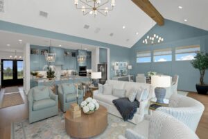 Spacious modern living room with blue walls, high ceiling, large windows, open kitchen, multiple sofas and chairs, round coffee table, and contemporary lighting—perfect for those seeking painted tree homes for sale in McKinney Texas.
