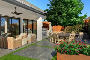 A modern patio with wicker seating, a dining table under a tree, a grill, potted flowers, and large glass doors leading inside—perfect for enjoying Painted Tree TX living.