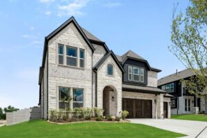 Two-story modern stone house with dark trim, large windows, wooden garage door, and landscaped front yard under a clear blue sky in the sought-after Painted Tree McKinney community.