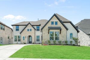 Two-story modern brick house with gabled roof, large windows, and a well-maintained front lawn under a blue sky in the sought-after Painted Tree McKinney community. Discover homes for sale in McKinney Texas today.