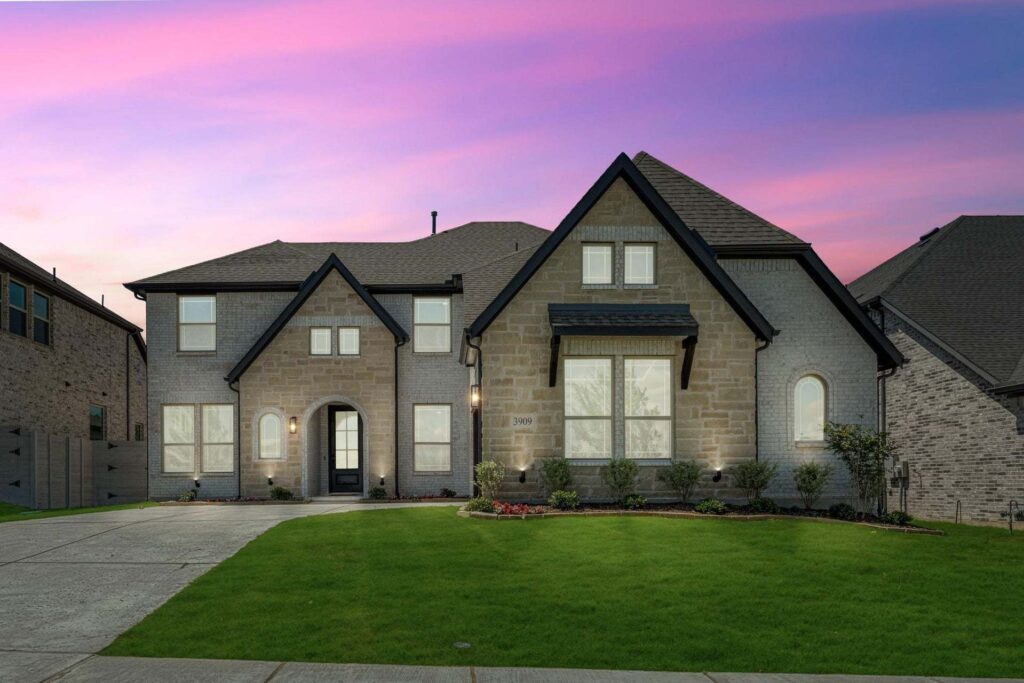 A two-story modern brick house with large windows, a manicured lawn, and a driveway, photographed at sunset under a pink and purple sky—one of the stunning painted tree homes for sale in McKinney, Texas.