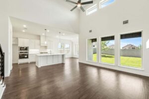 Spacious, modern open-plan living area with large windows, high ceiling, and a stylish kitchen overlooks a green backyard—perfect for those seeking homes for sale in McKinney, Texas.