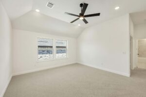 Empty, carpeted room with two windows, white walls, a black ceiling fan, and a doorway leading to an adjacent area—experience comfortable living in the heart of Painted Tree McKinney.