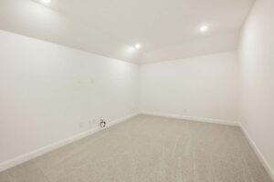 Empty room with beige carpet, white walls, recessed ceiling lights, and several electrical outlets along the lower walls—perfect for those exploring homes for sale in McKinney, Texas.