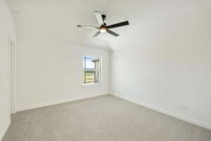 Empty room with beige carpet, white walls, a window with outdoor view, and a sleek black ceiling fan—ideal for those seeking Painted Tree homes for sale or exploring homes for sale in McKinney, Texas.