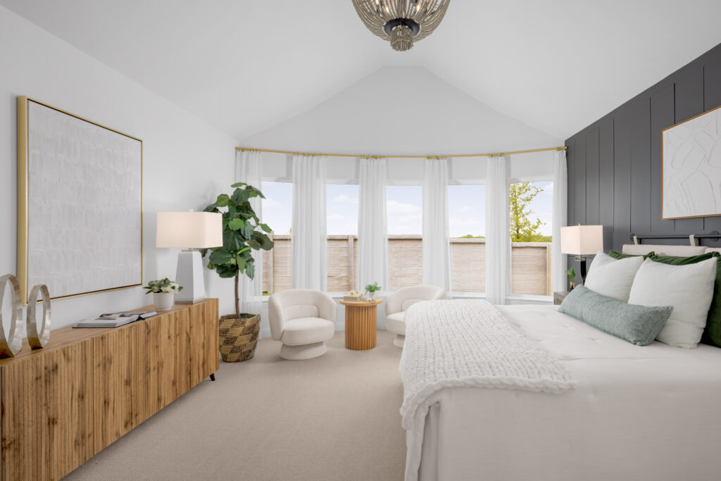 Modern bedroom in a new home with a vaulted ceiling, large windows, neutral decor, wooden dresser, two armchairs, a potted plant, and a bed with white bedding and green accents—crafted by Coventry Homes in TX.