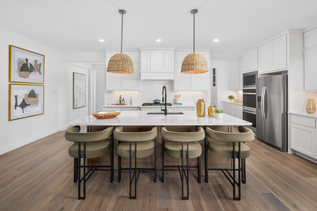 Modern kitchen in a new McKinney, TX home featuring white cabinets, stainless steel appliances, a spacious island with four green bar stools, and two woven pendant lights above.