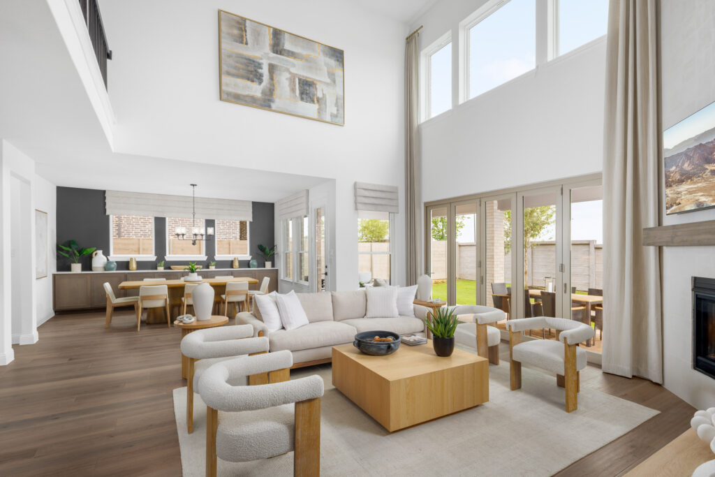 A modern, open-concept living and dining area in this Coventry Homes new home features large windows, neutral furnishings, wood flooring, and abundant natural light—perfect for comfortable McKinney living.